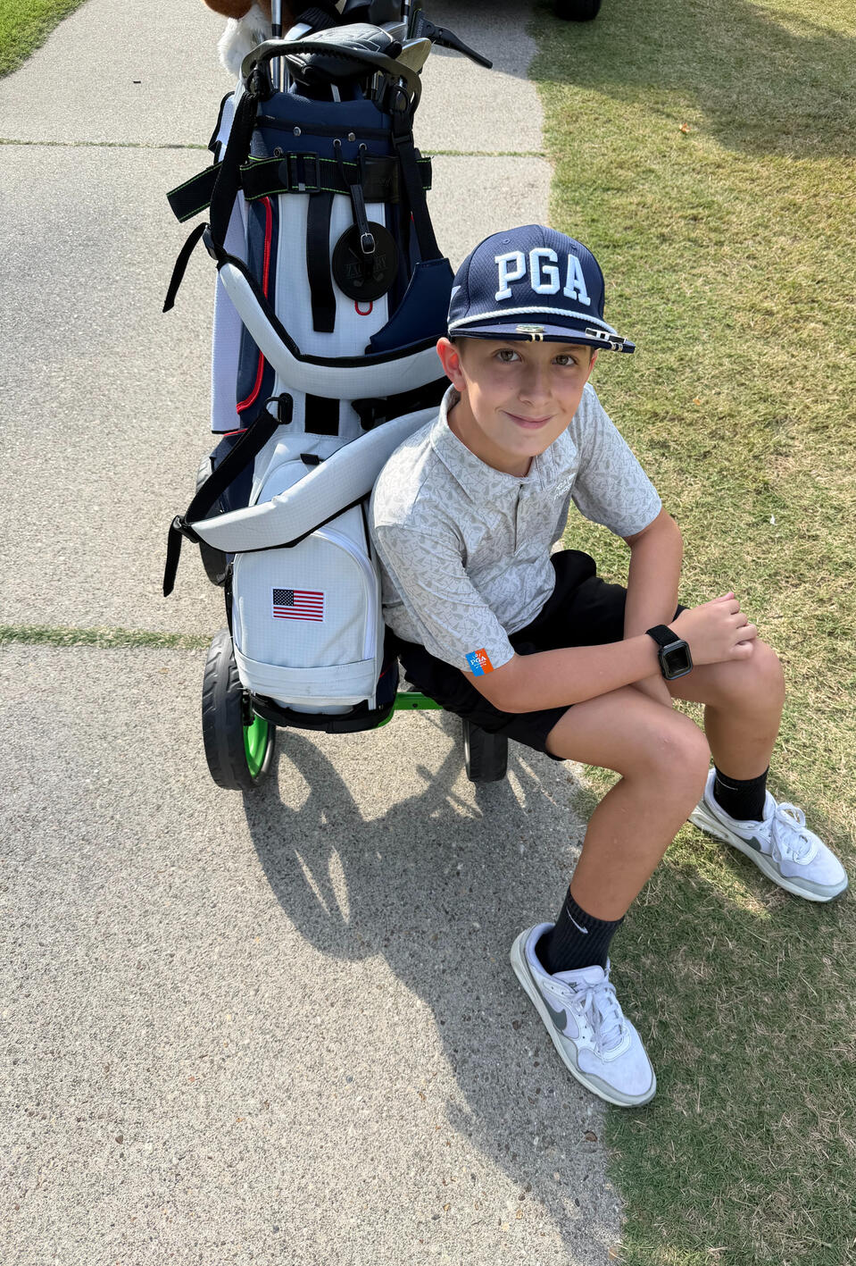 Zachary Walker | Golfer Zachary Walker sitting beside his golf bag at a golf course, wearing a PGA hat.